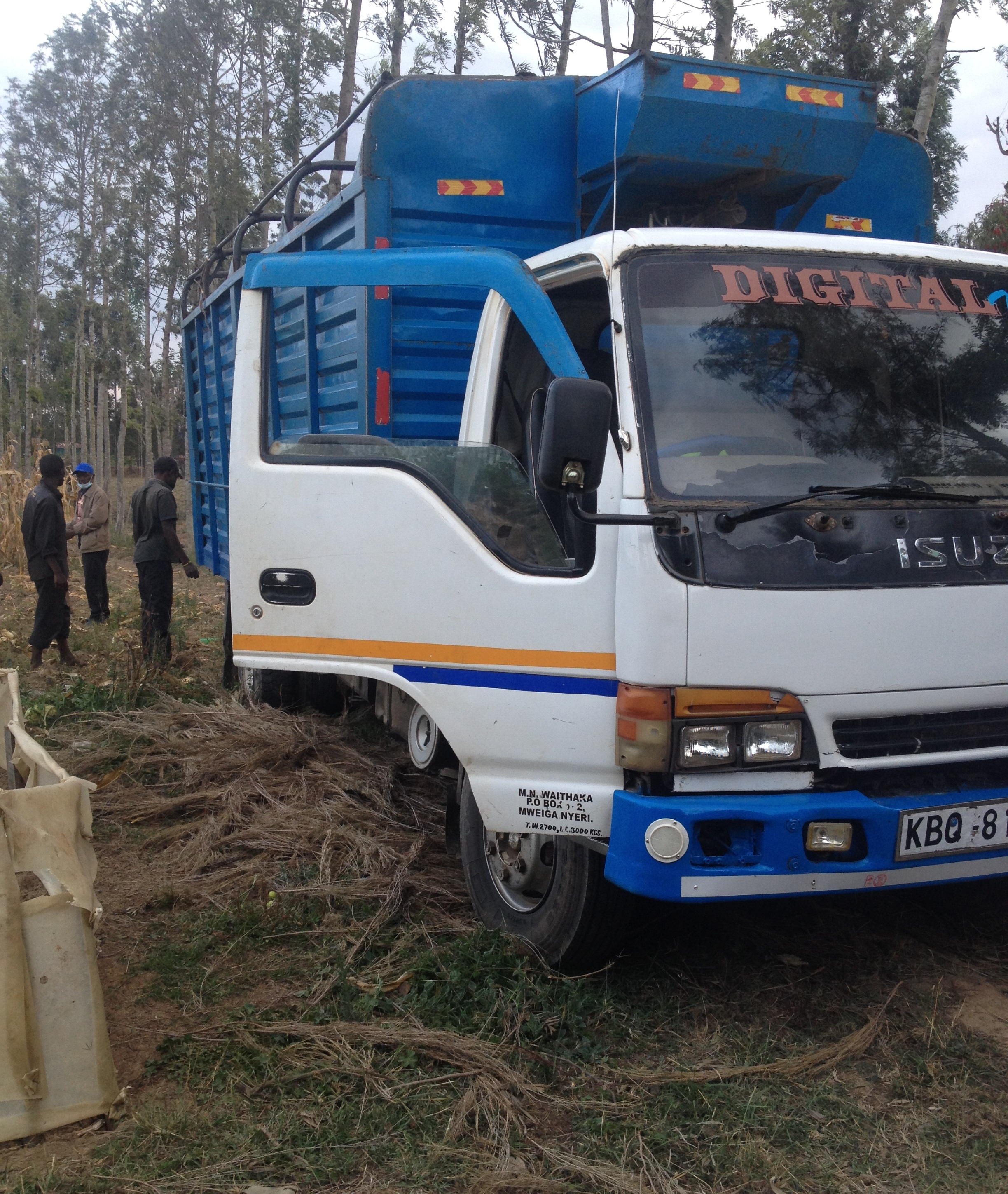 a lorry parked in a farm with people behind unloading manure