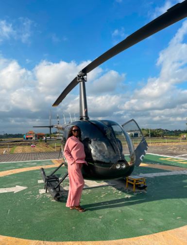 A lady stands besides a helicopter charter service
